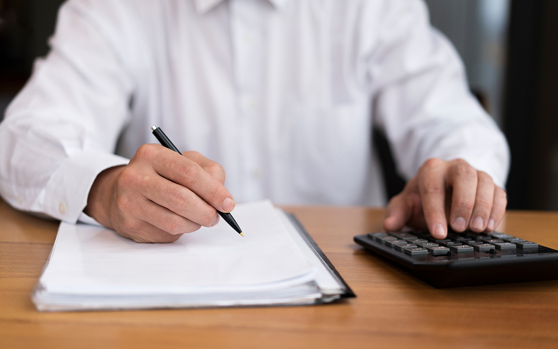 Hands calculating and writing down laundry business operating costs.